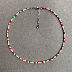 a red, green and white beaded necklace on a silver chain