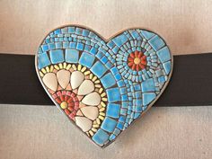 a blue heart shaped brooch with flowers on it's side and a black belt