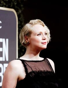 a close up of a person wearing a black dress and looking off to the side