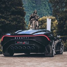 a black sports car parked in front of a statue