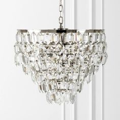 a crystal chandelier hanging from the ceiling in front of a white painted wall