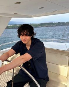 a man sitting on the back of a boat in the water with his hand on the railing