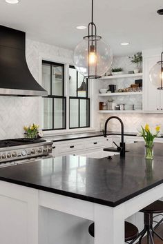 a kitchen with an island and two pendant lights hanging over it's counter tops