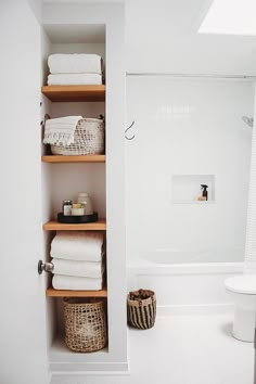 a bathroom with white walls and shelves filled with towels