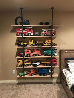 a room with a bed and shelves filled with toy trucks on top of each shelf