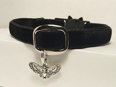 a black dog collar with a silver butterfly charm on it's front and back