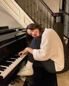 a woman is playing the piano in front of some stairs and railings with her hands on the keyboard