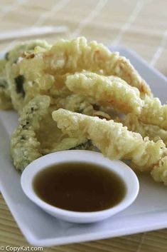 some fried food on a white plate with dipping sauce