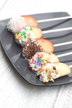 a black plate topped with different types of donuts and sprinkles on top of each other