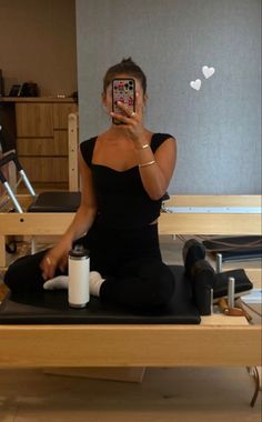 a woman is sitting on a yoga mat and taking a selfie with her phone