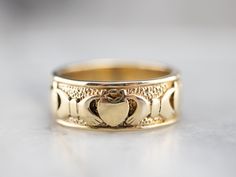 a gold wedding ring with two hearts in the center on a white surface, close up