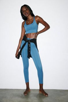 a woman in blue sports bra and leggings posing for the camera with her hands on her hips