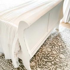 a white bed sitting on top of a rug next to a window