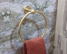 a gold towel ring in a bathroom with marble walls and flooring, along with red towels