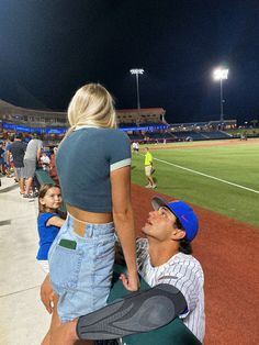 a man and woman sitting on a bench at a baseball game