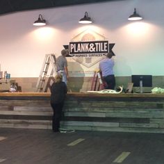 two people are standing at the front desk of plank & tile, which is under construction