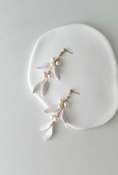 two white flowers with pearls on them are shown in front of a white plate,