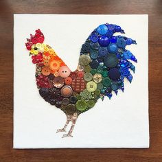 a rooster made out of buttons on a white canvas