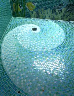 a bathroom with blue and green mosaic tiles on the floor, shower head in the center