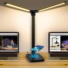 two laptops sitting on top of a wooden desk next to each other with lights above them