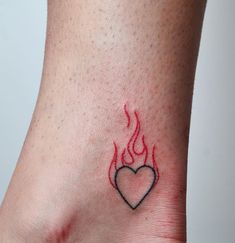 a small tattoo on the ankle of a woman with a heart and flames drawn on it