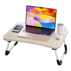 an open laptop computer sitting on top of a wooden table next to a coffee cup