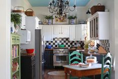 a kitchen with white cabinets and black and white checkered wallpaper, green chairs, and a table in front of the stove