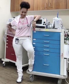 a woman sitting on top of a medical cart in a room with lots of drawers