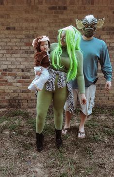 two people in costumes standing next to a brick wall and one is holding a doll