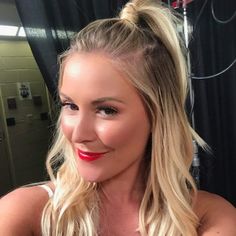 a woman with long blonde hair and red lipstick is looking at the camera while wearing a white tank top