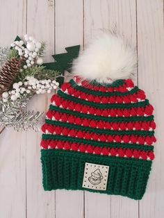 a red, green and white knitted hat with a pom - pom