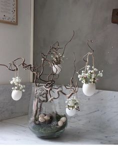 a vase filled with flowers and rocks on top of a table next to a mirror