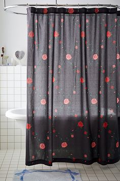 a shower curtain with red flowers on it in a white tiled bathtub area next to a toilet and sink