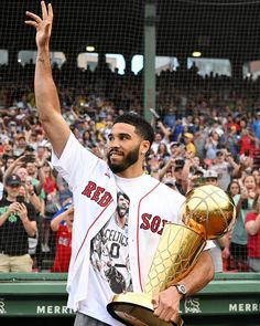 a man waves to the crowd as he holds up his trophy in front of him