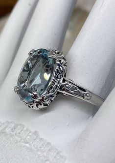 a fancy ring with an aqua blue topazte surrounded by filigrees