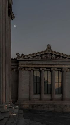 an old building with columns in front of it and the moon rising over the horizon