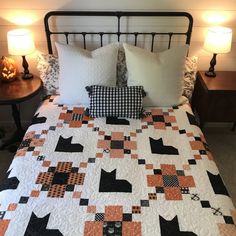 a black and white cat quilt on a bed with two night stands next to it