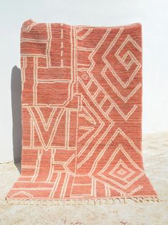 an orange and white rug sitting on top of a cement floor next to a wall