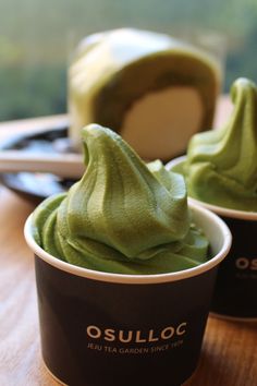 two cups filled with green cream on top of a wooden table