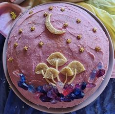 a pink cake with mushrooms and stars on it's icing is sitting on a plate