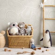 stuffed animals in a basket next to a ladder and wallpaper with wavy design on it