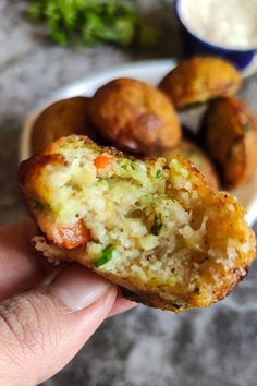 a hand holding up a half eaten muffin in front of some other food items