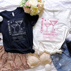 two t - shirts with cocktails on them are laying next to other clothing and accessories