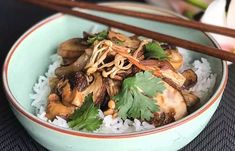 a blue bowl filled with rice and vegetables next to chopsticks on a table