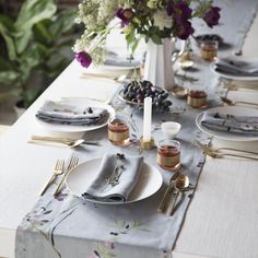 the table is set with plates and silverware, flowers in vases, and napkins