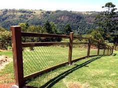 a wooden fence on top of a lush green hillside