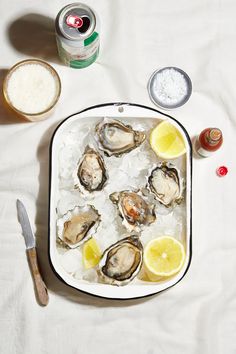 oysters on an ice tray with lemon wedges, salt and pepper