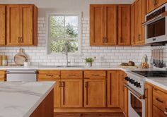 a kitchen with wooden cabinets and marble counter tops, along with white subway tile backsplash