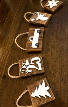 four small wooden boxes with white designs on them sitting on a wood table next to some scissors