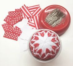 some red and white items sitting on top of a table next to a pin cushion